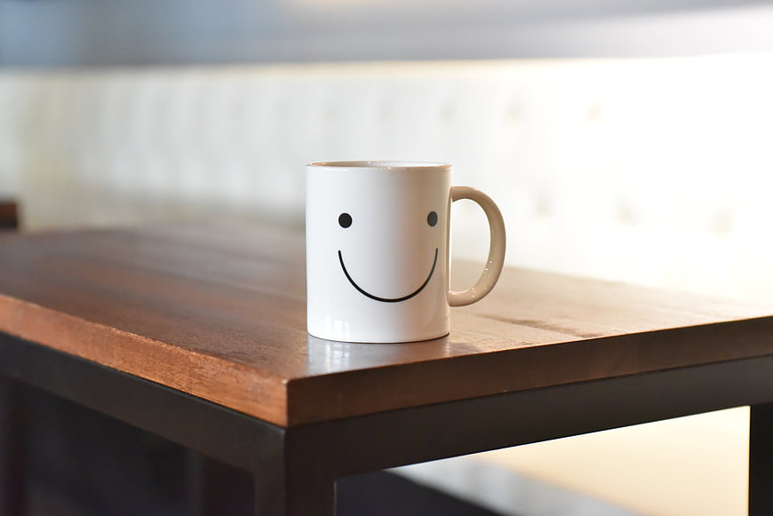 White Ceramic Mug With Smiley Face On Wooden Table