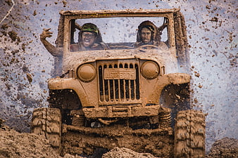 Off-road Jeep splashing through deep mud with two people