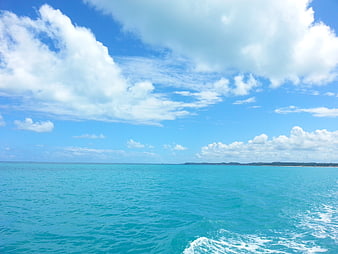 Tropical turquoise ocean waters and bright blue sky with clouds