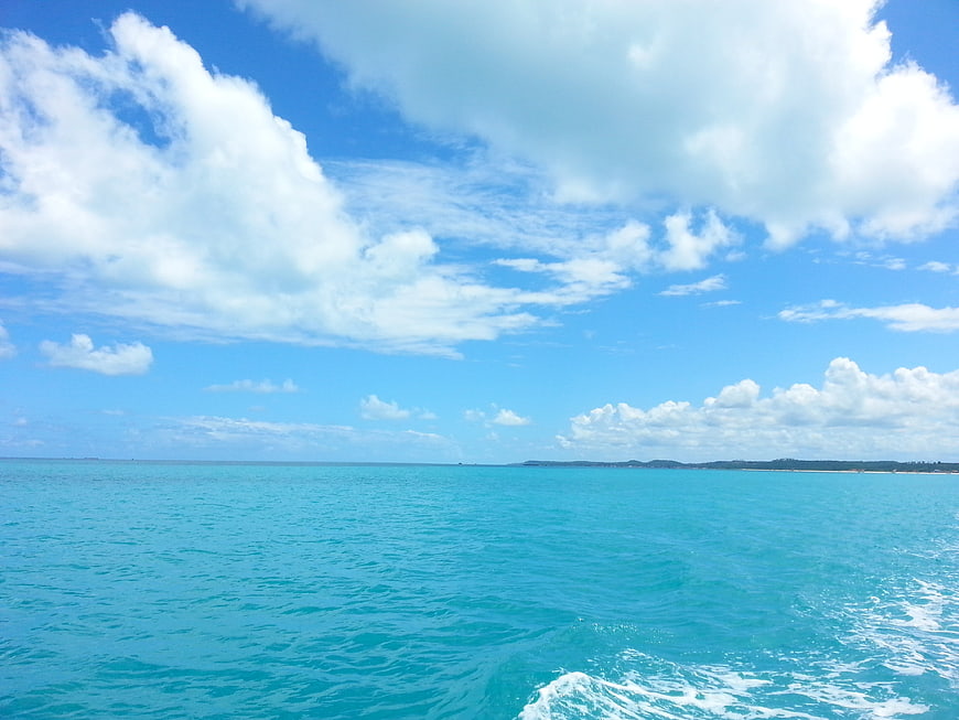 Tropical turquoise ocean waters and bright blue sky with clouds