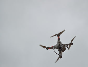 White Quadcopter Drone Flying Against Overcast Sky
