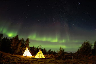 Illuminated Tents Under Northern Lights and Starry Night Sky