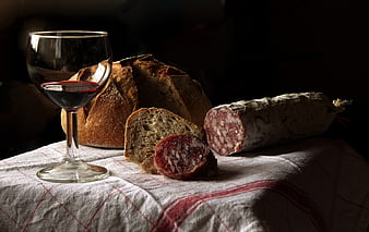 Rustic red wine, bread, and salami on checkered tablecloth