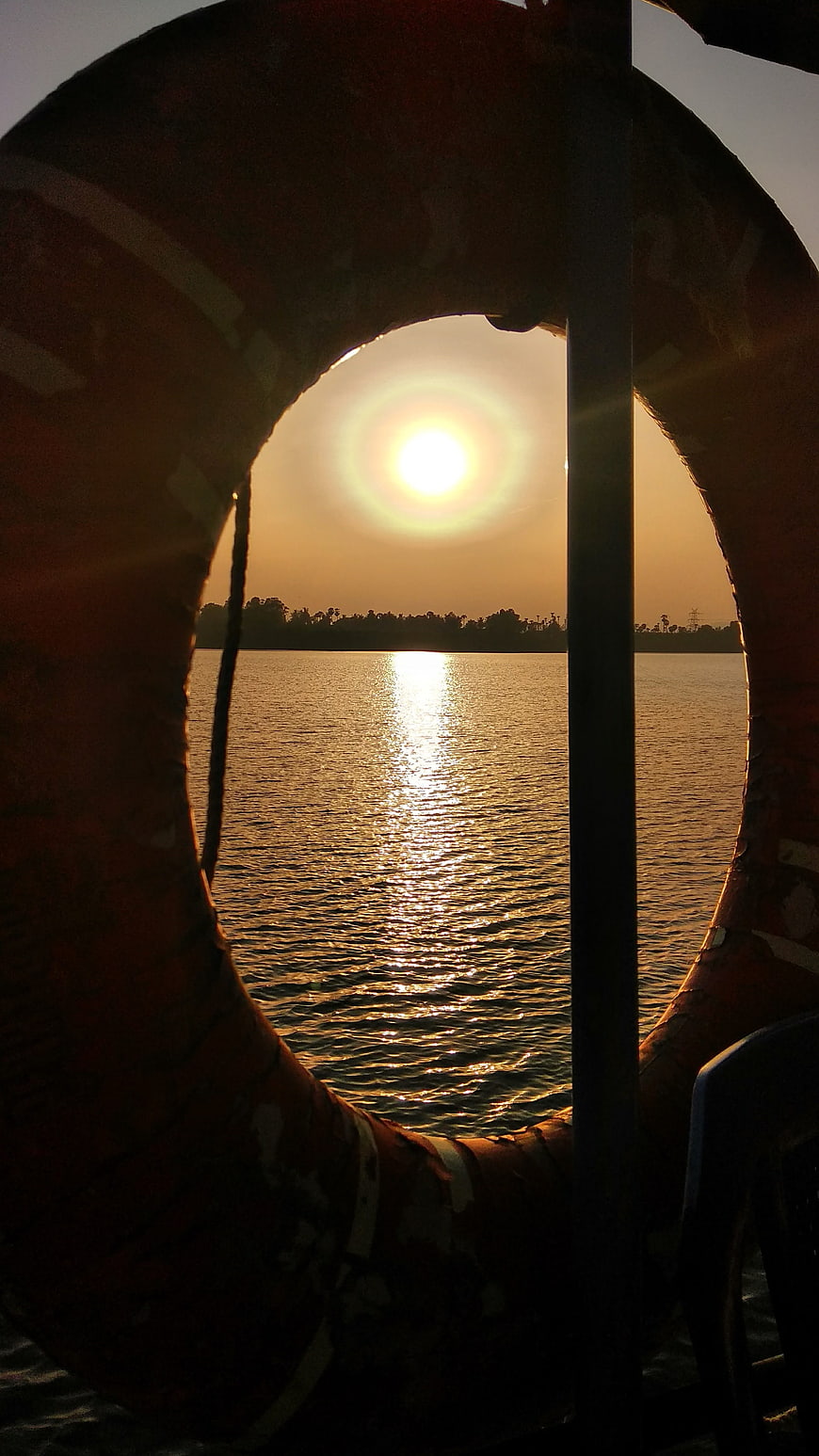 Sunset View Through Silhouetted Lifebuoy on River