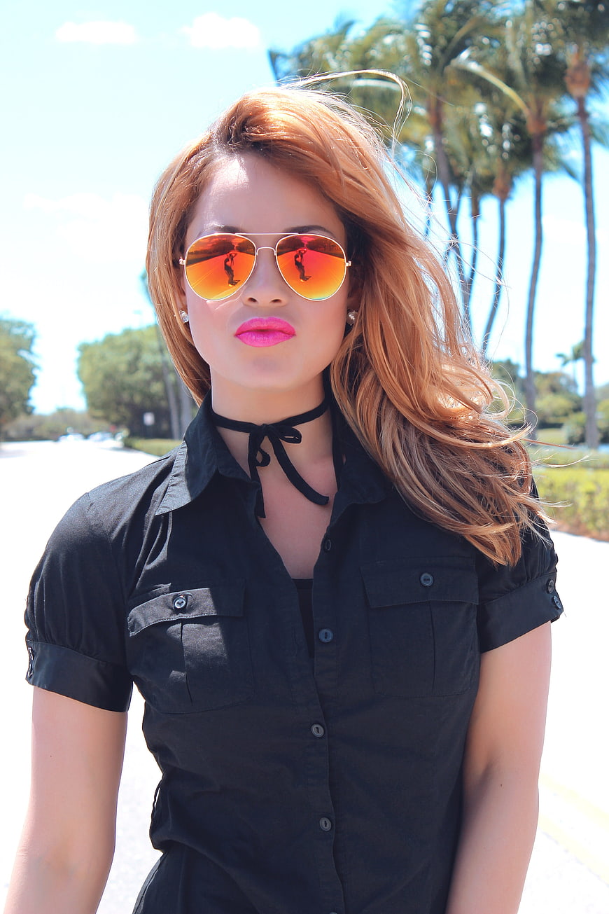 Young woman with red hair and orange sunglasses in black shirt