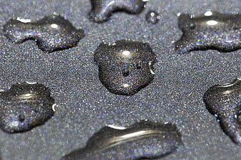 Macro shot of water droplets on dark glittery surface