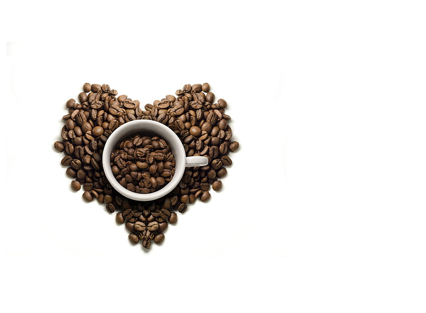 Heart shape made of coffee beans with white cup on white background