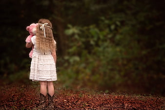 Little Girl in Cowboy Boots Holding Pink Teddy Bear in Forest