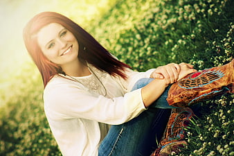 Smiling Redhead Woman in Cowboy Boots Sitting in Clover Field