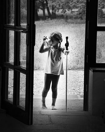 Black and white photo of a young girl with a sword and cup