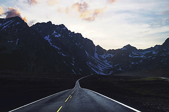 Winding Mountain Road at Dusk with Snowy Peaks