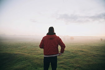 Man in Red Jacket Standing in Misty Field