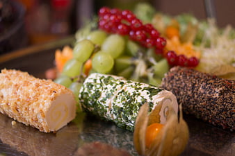 Gourmet cheese logs with herbs and fruits on a platter