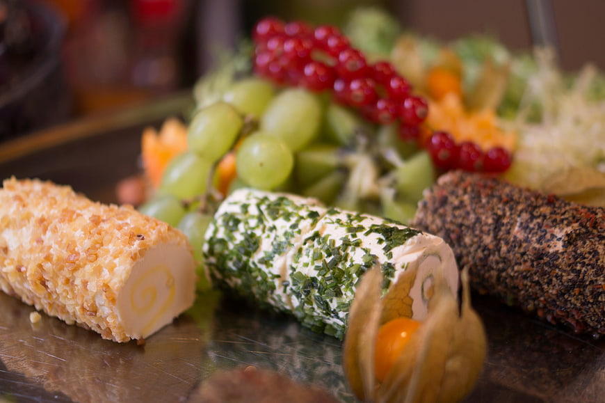 Gourmet cheese logs with herbs and fruits on a platter