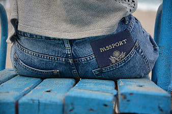 Passport in back pocket of jeans on blue bench