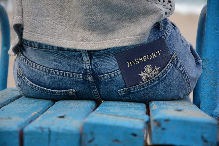 Passport in back pocket of jeans on blue bench