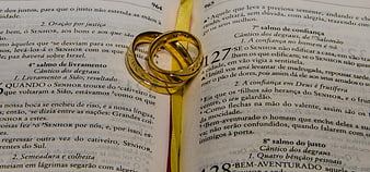 Gold wedding rings on open Portuguese Bible pages