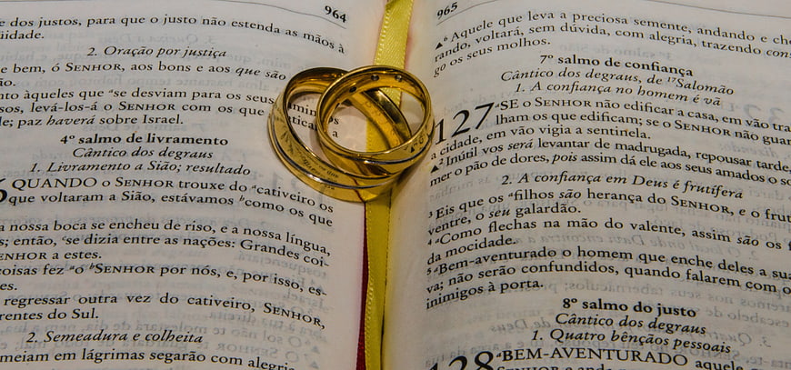 Gold wedding rings on open Portuguese Bible pages