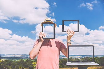 Man holding tablet and laptop outdoors with sky reflection