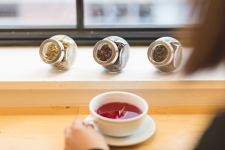 Cup of Red Tea with Herbal Jars on Wooden Table