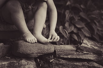 Sepia photo of child's bare feet on rocks in nature