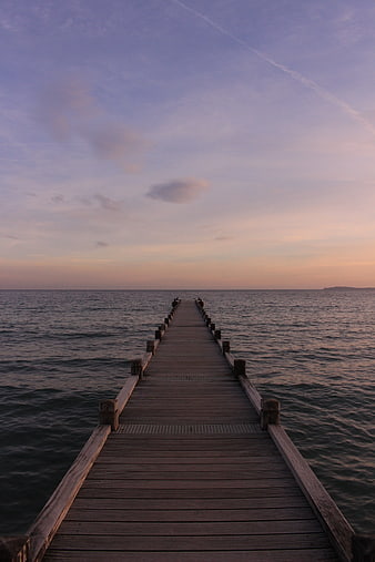 Wooden Pier Extending into Calm Sea at Sunset