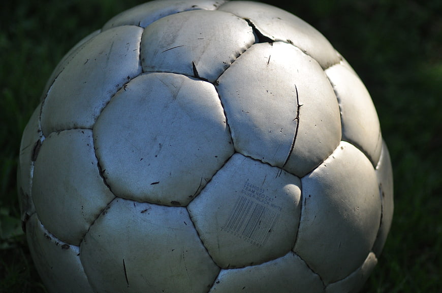 Close-up of worn silver soccer ball on grass