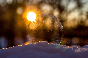 Ice Sphere Reflecting Golden Sunset in Snow