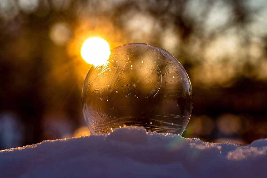 Ice Sphere Reflecting Golden Sunset in Snow