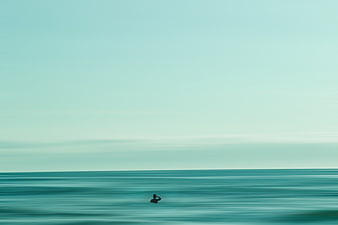 Minimalist Silhouette of Surfer in Teal Ocean