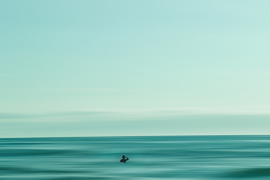 Minimalist Silhouette of Surfer in Teal Ocean