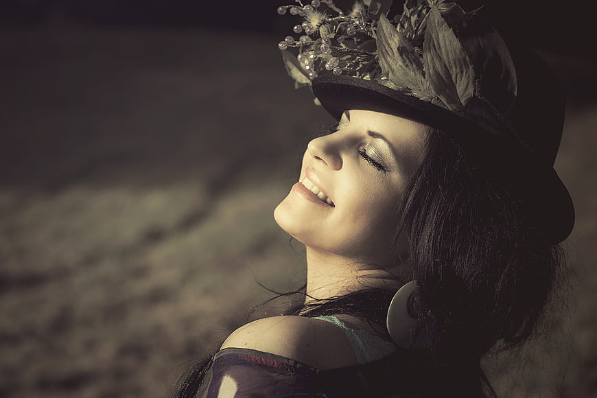 Happy woman wearing floral hat smiling with eyes closed