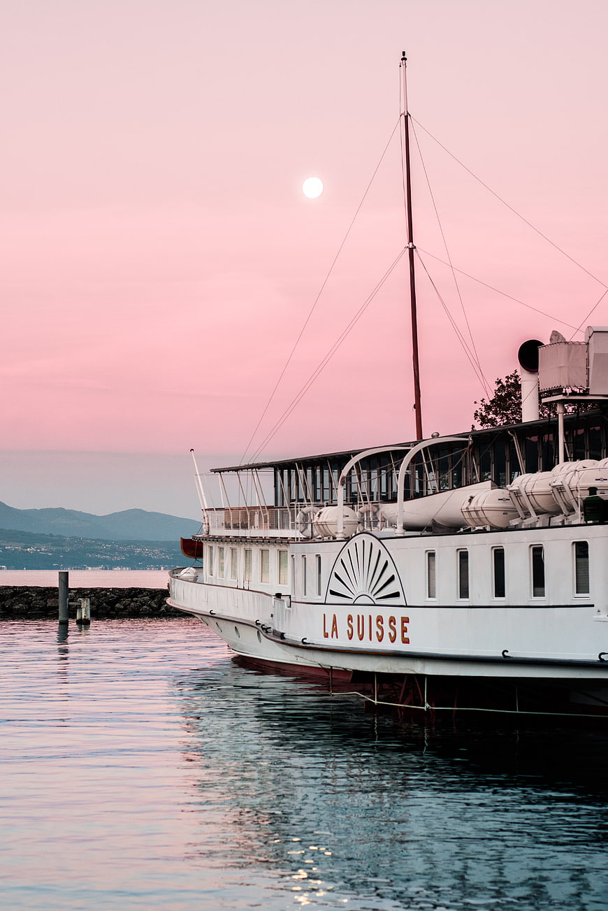 Vintage boat La Suisse docked at sunset with pink sky
