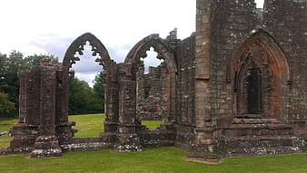 Gothic stone church ruins with arched windows in green field