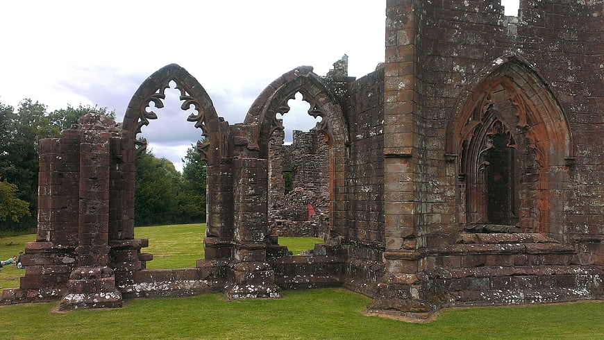 Gothic stone church ruins with arched windows in green field