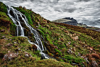 Dramatic waterfall cascading down mossy rocks in Scottish Highlands