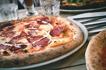 Close-up of Salami Pizza with Cheese Drizzle on Wooden Table