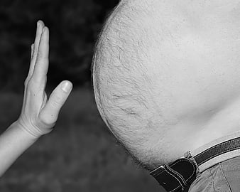 Black and white close-up of a hand stopping an obese belly