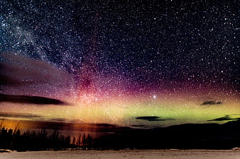 Milky Way and Aurora Borealis over Snowy Winter Landscape
