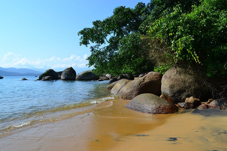 Tropical Beach with Large Boulders and Lush Green Trees
