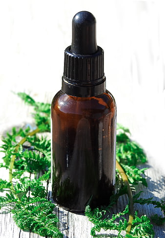 Amber Glass Dropper Bottle with Ferns on White Wood
