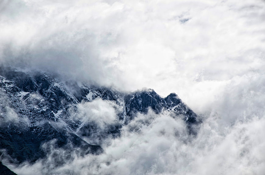 Snowy mountain peaks emerging through thick clouds