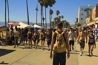 Man with Backpack Walking on Busy Venice Beach Boardwalk