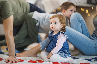 Toddler girl sitting on floor with family playing game