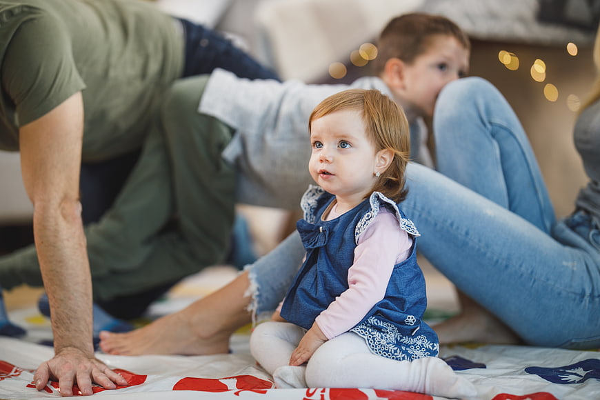 Toddler girl sitting on floor with family playing game