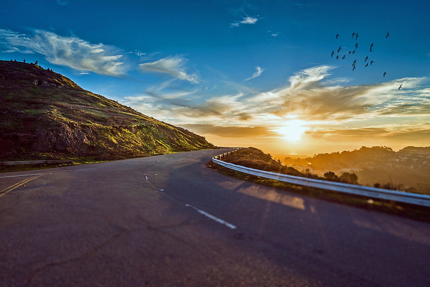 Winding Mountain Road at Sunset with Birds Flying