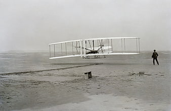 Historical Wright Brothers Flyer Aircraft Hovering Over Sand Dunes