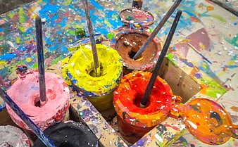 Colorful paint pots with brushes on a messy artist palette