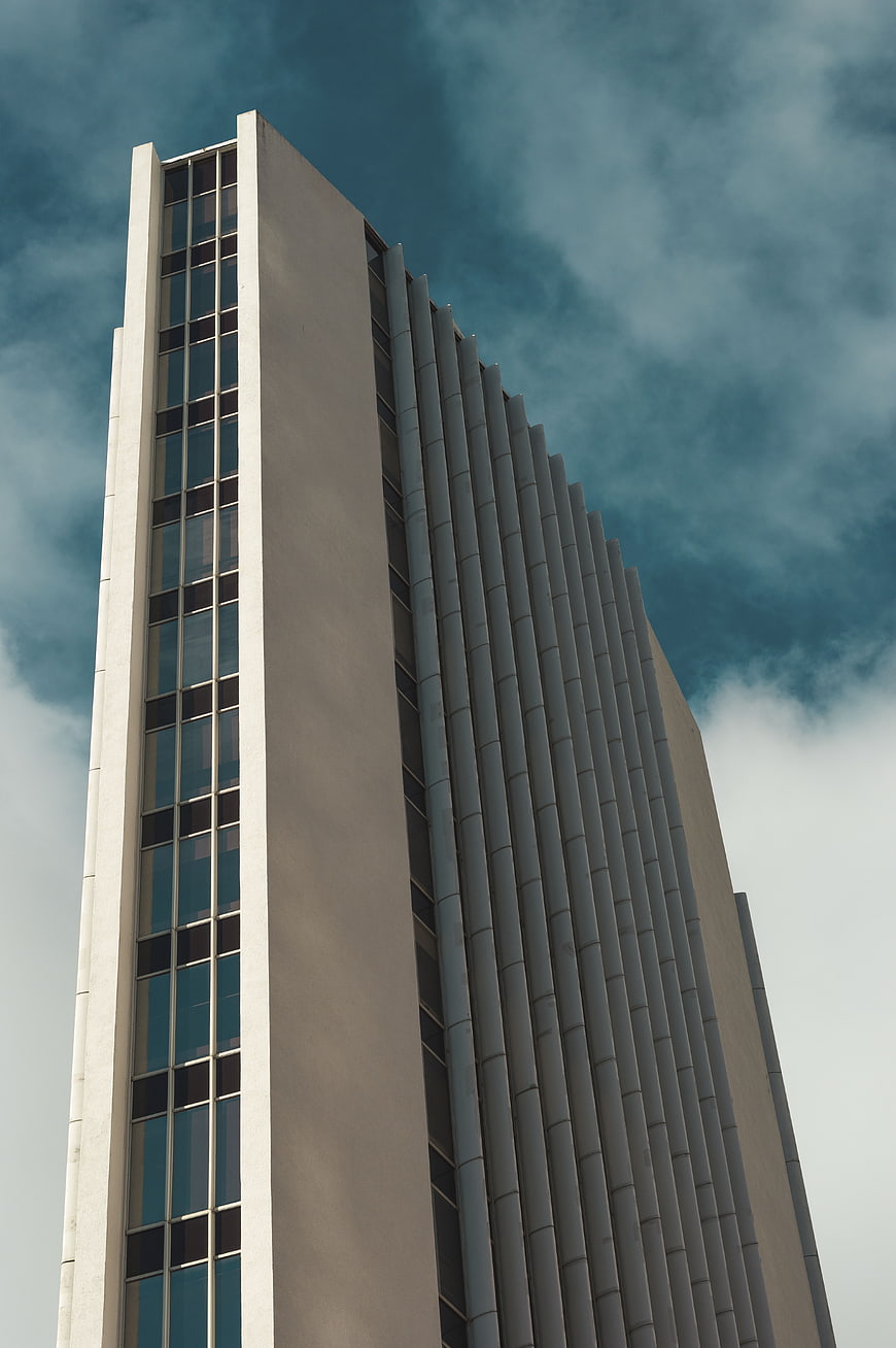 Modern High-Rise Building with Vertical Lines Against Cloudy Sky
