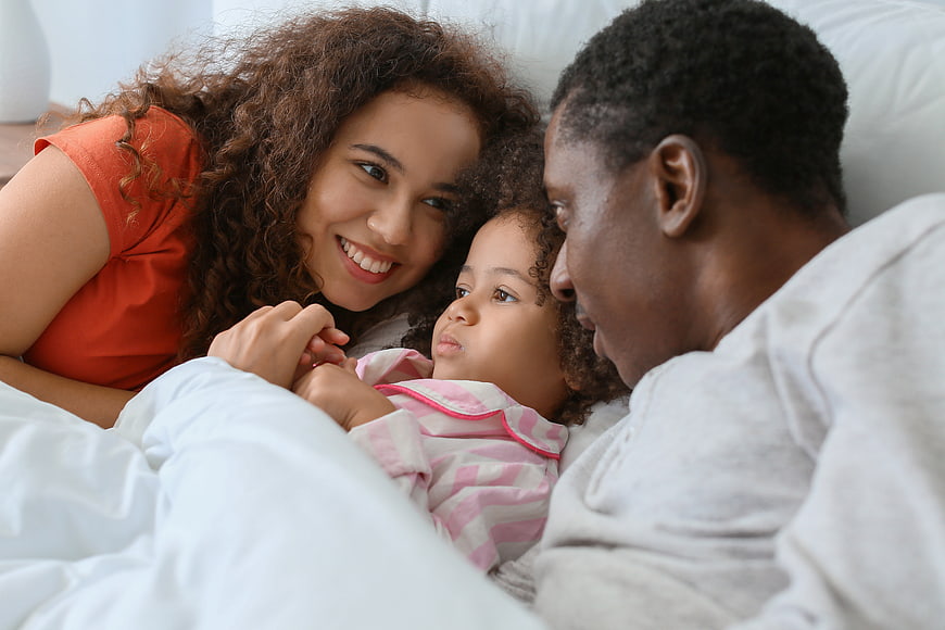 Happy African American Family in Bed with Toddler